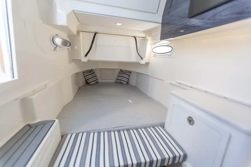 Slide: The Image of Manufacturer Provided Image: 2024 Cobia 350 Center Console cabin interior with striped cushions and porthole windows. - 40