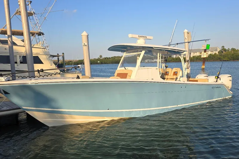 The Image of 2024 Cobia 350 Center Console boat docked on calm water under clear sky. - 0