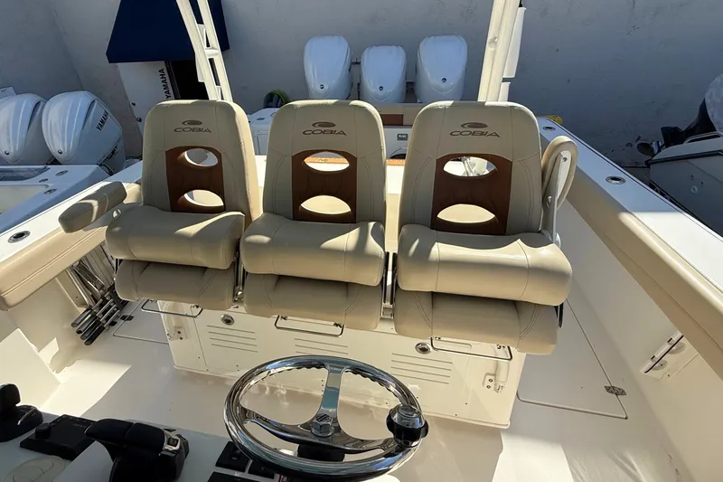 Slide: The Image of 2024 Cobia 350 Center Console boat with three cushioned seats and steering wheel. - 20