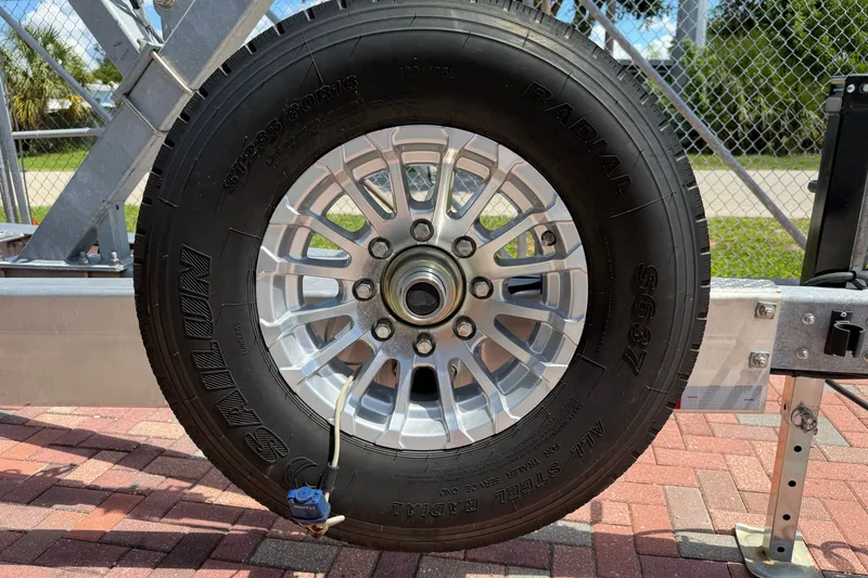 Slide: The Image of Trailer wheel for 2024 Cobia 350 Center Console boat on brick pavement. - 54