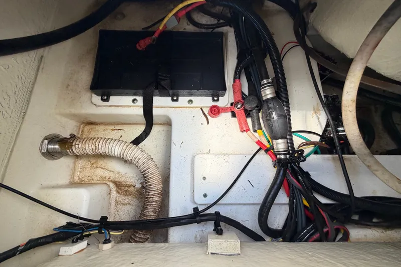 Slide: The Image of A view inside the engine compartment of a 2023 Wellcraft 202 Fisherman boat, showing cables and hoses. - 48