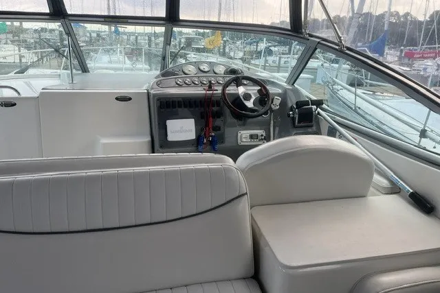 Slide: The Image of 2006 Maxum 3300 SE boat interior with helm, steering wheel, and seating in a marina setting. - 6