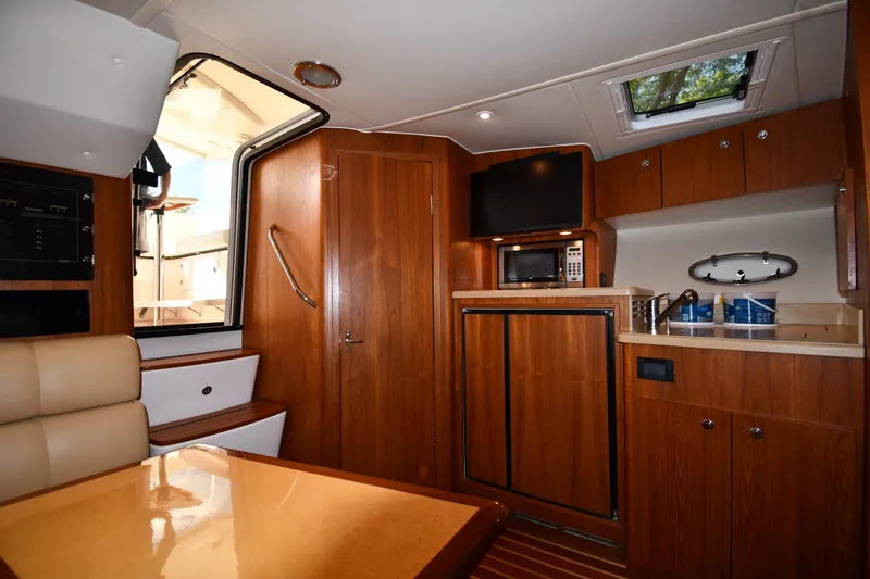 Slide: The Image of 2004 Tiara Yachts 3500 Open interior with wood cabinetry, kitchenette, and seating area. - 33