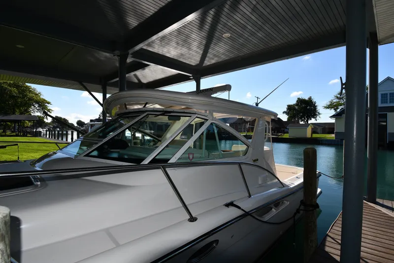 Slide: The Image of 2004 Tiara Yachts 3500 Open docked under a covered marina with scenic waterfront view. - 1