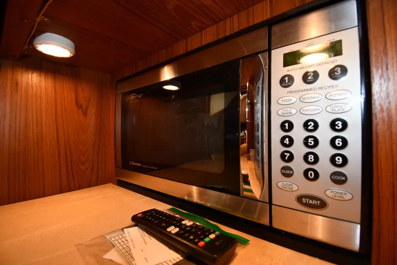 Slide: The Image of Microwave in 2004 Tiara Yachts 3500 Open, wooden cabinetry, remote control nearby. - 37