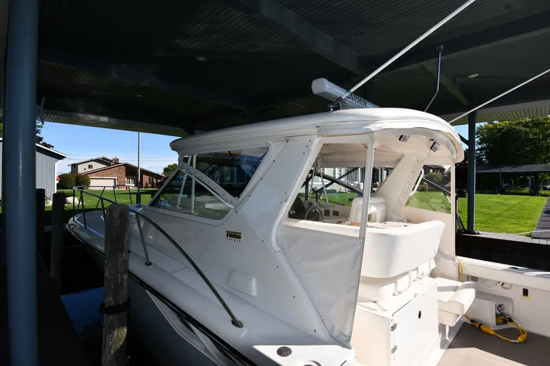 Slide: The Image of 2004 Tiara Yachts 3500 Open docked under a covered marina with lush surroundings. - 2