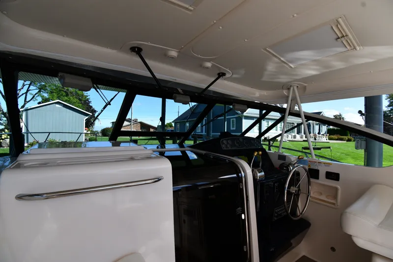Slide: The Image of 2004 Tiara Yachts 3500 Open cockpit with steering wheel and controls, docked near houses. - 8