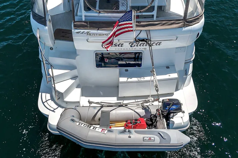 Slide: The Image of 2008 Cruisers Yachts 415 Express Motoryacht with dinghy and American flag on water. - 15