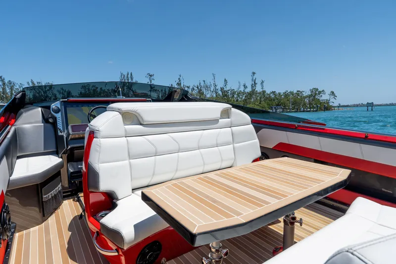 Slide: The Image of 2023 Nor-Tech 55 Flyer boat interior with white seating and wooden table on a sunny day. - 36