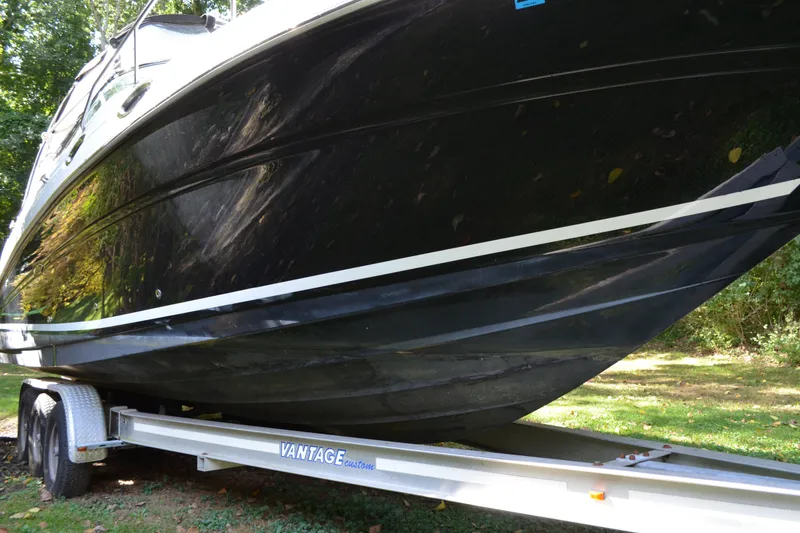 Slide: The Image of 2007 Sea Ray Sundancer 280 boat on trailer, black hull, parked on grass. - 2