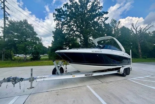 The Image of 2017 Monterey 264FS boat on trailer in parking lot, surrounded by trees and cloudy sky. - 1