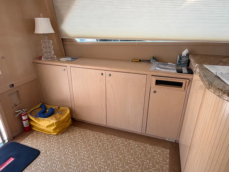 Slide: The Image of Interior of a yacht with wooden cabinets, carpeted floor, and a table lamp. A fire extinguisher is in the corner. - 22
