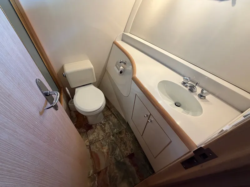 Slide: The Image of A sleek bathroom with a toilet, sink, and marble tile floor on a Heisley Marine Custom 70 yacht. - 24