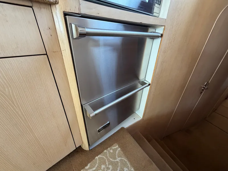 Slide: The Image of A modern stainless steel refrigerator with two handles in a boat kitchen, surrounded by wood paneling. - 16