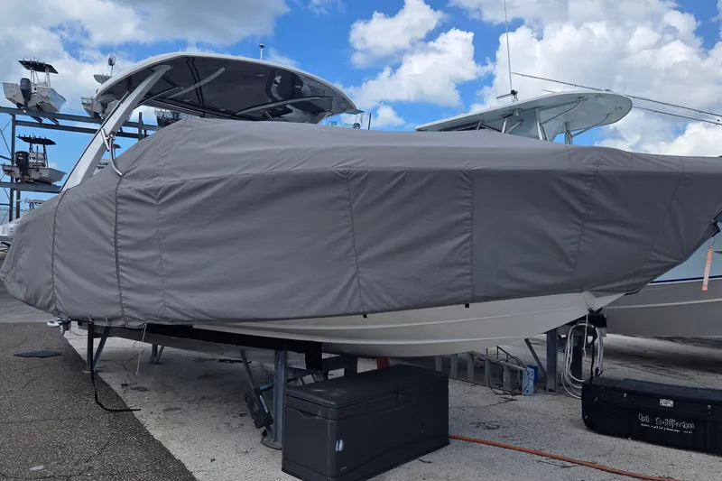 Slide: The Image of 2023 Cobalt 30SC Outboard boat covered, docked under a cloudy sky. - 28