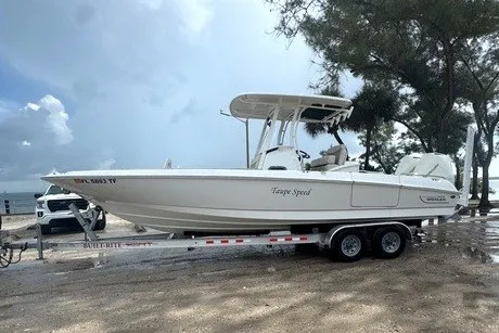 Slide: The Image of 2022 Boston Whaler 270 Dauntless boat on trailer, parked near trees and cloudy sky. - 33