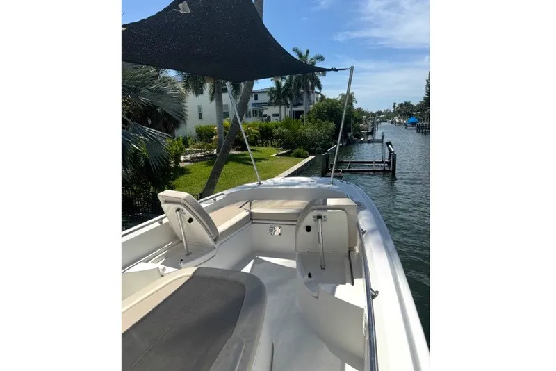 Slide: The Image of 2022 Boston Whaler 270 Dauntless boat with seating, canopy, and scenic waterfront view. - 28