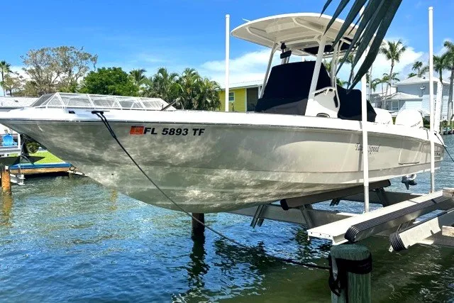Slide: The Image of 2022 Boston Whaler 270 Dauntless boat on lift, docked in sunny waterfront setting. - 1