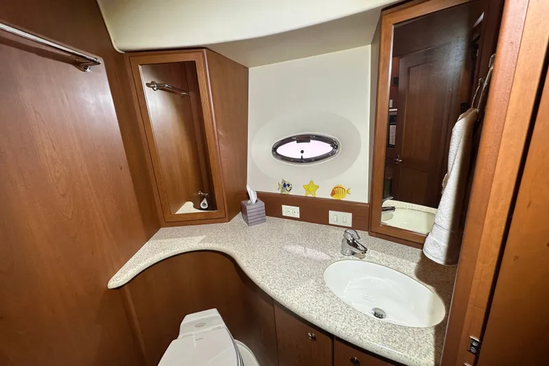 Slide: The Image of 2005 Silverton 43 Motor Yacht bathroom with wooden cabinetry and oval window. - 36