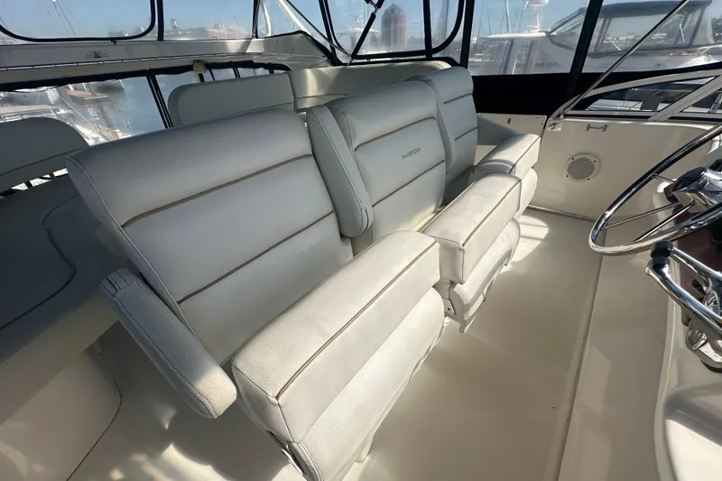 Slide: The Image of 2005 Silverton 43 Motor Yacht helm with white cushioned seating and steering wheel. - 20