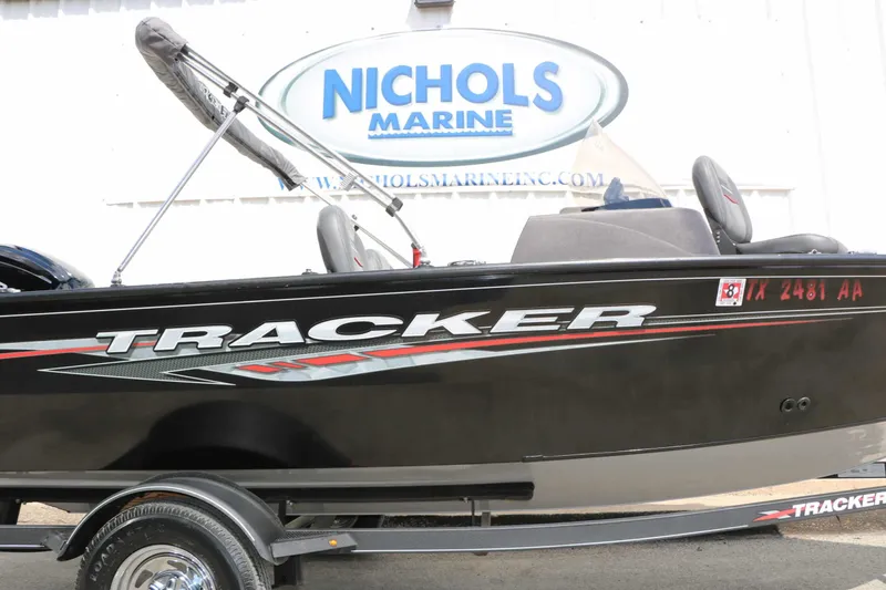 Slide: The Image of A black Tracker boat, model Pro Guide V16, is on a trailer in front of a building with a "Nichols Marine" sign. - 28