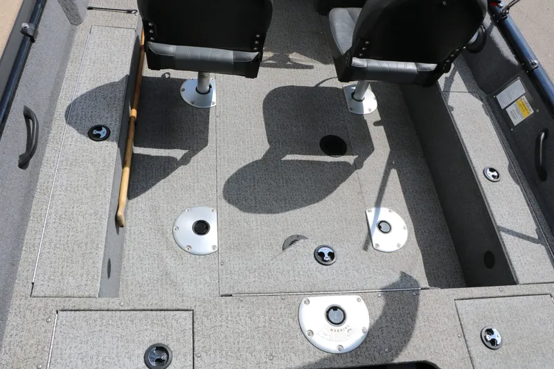 Slide: The Image of The image shows the cockpit of a 2023 Tracker Pro Guide V16 boat with gray carpeting and two black seats. - 23