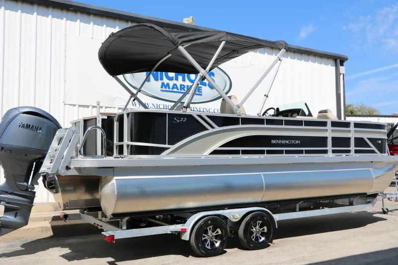 Slide: The Image of A 2027 Bennington 22 SF Tri Toon on a trailer in front of a building. It features a black canopy and a Yamaha engine. - 14