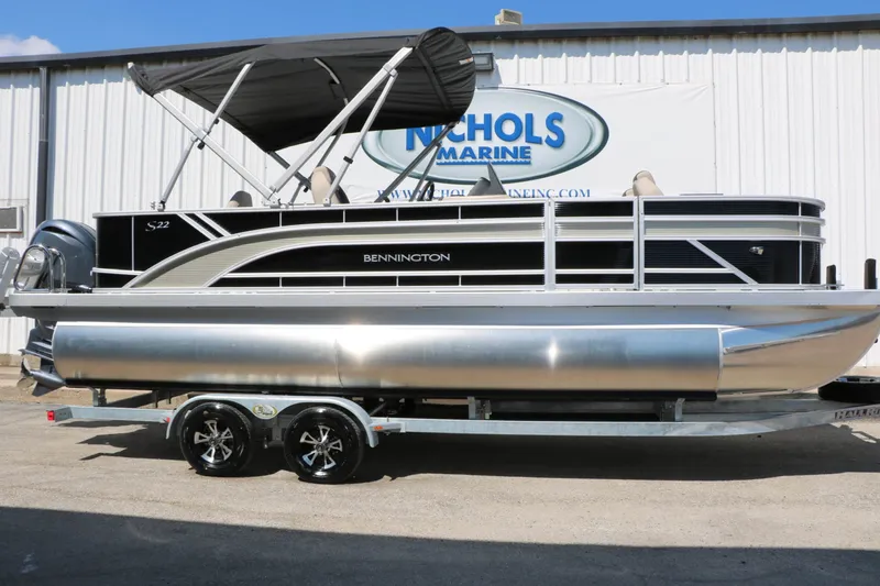 Slide: The Image of A 2027 Bennington 22 SF Tri Toon on a trailer in front of a building. - 2