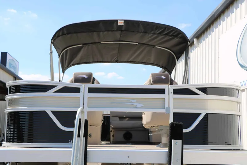Slide: The Image of A 2027 Bennington 22 SF Tri Toon with a black Bimini top and beige seats. - 8