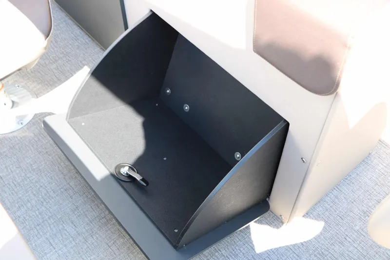 Slide: The Image of An open storage compartment on a Bennington 22 SF Tri Toon boat, featuring carpeted flooring and upholstery. - 48
