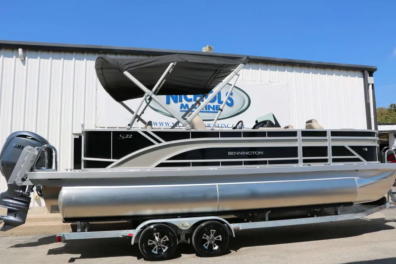 Slide: The Image of A 2027 Bennington 22 SF Tri Toon on a trailer in front of a building. - 13