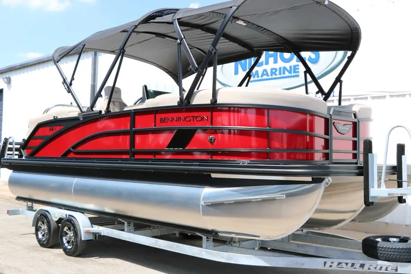 Slide: The Image of A red 2027 Bennington 22 MFB Tri Toon on a trailer, featuring a black canopy. - 6