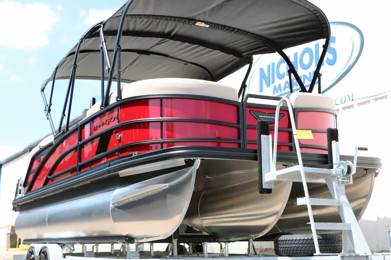 Slide: The Image of A red 2027 Bennington 22 MFB Tri Toon on a trailer, featuring a black canopy. - 8