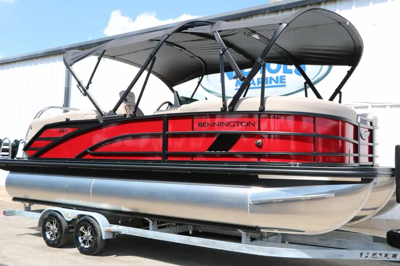 Slide: The Image of A red 2027 Bennington 22 MFB Tri Toon on a trailer, featuring a black canopy. - 5