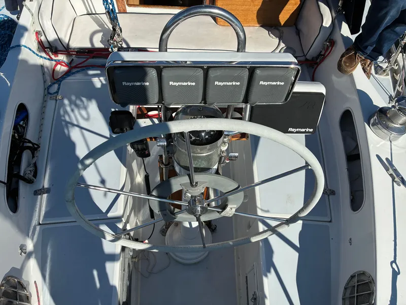 Slide: The Image of The cockpit of a 1973 Pearson 36 with a large steering wheel and Raymarine instruments. - 20