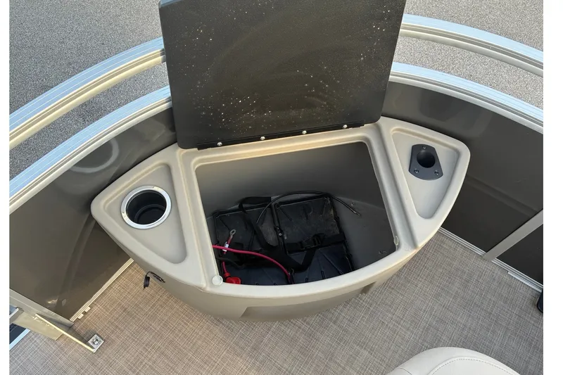 Slide: The Image of 2025 Sun Tracker Fishin' Barge 20 DLX storage compartment with cup holders and battery. - 19