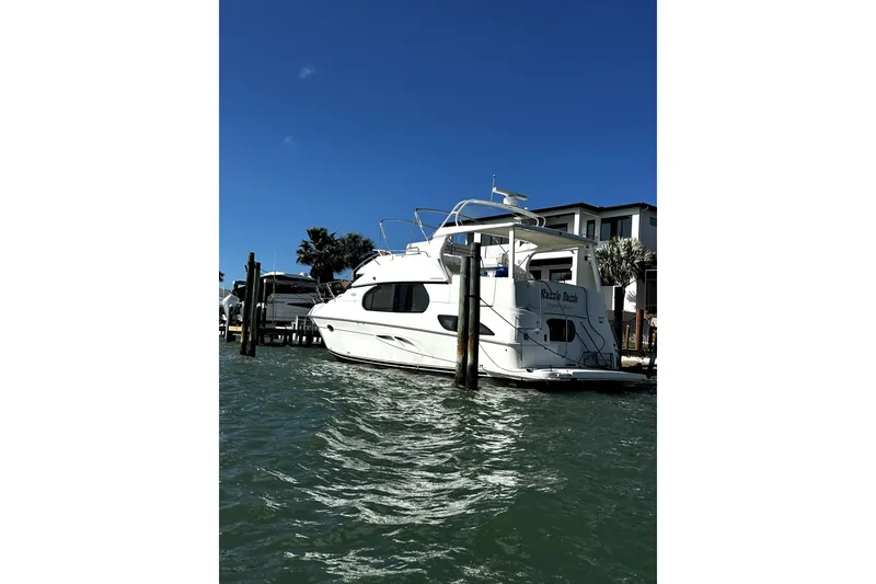 Slide: The Image of 2004 Silverton 43 Motor Yacht docked by waterfront homes under clear blue sky. - 1
