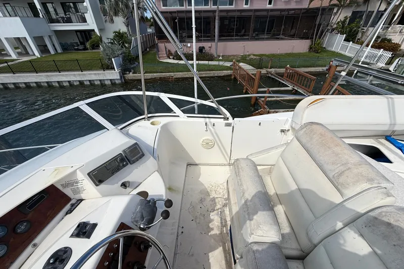 Slide: The Image of 2004 Silverton 43 Motor Yacht helm with seating, overlooking waterfront homes. - 40