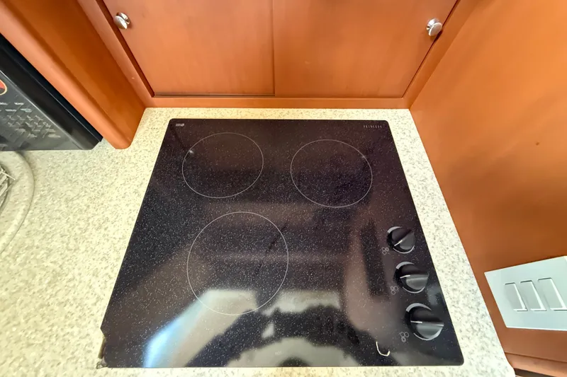 Slide: The Image of Glass cooktop in 2004 Silverton 43 Motor Yacht kitchen, featuring four burners and control knobs. - 100