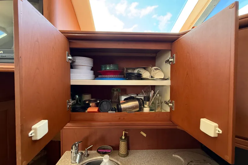 Slide: The Image of Open kitchen cabinet on 2004 Silverton 43 Motor Yacht, showing dishes and kitchenware. - 106