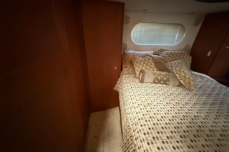 Slide: The Image of Cozy bedroom interior of 2004 Silverton 43 Motor Yacht with patterned bedding and window blinds. - 163
