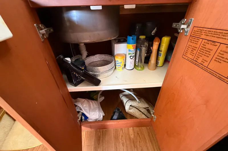 Slide: The Image of Open cabinet under sink on 2004 Silverton 43 Motor Yacht, storing cleaning supplies and miscellaneous items. - 110