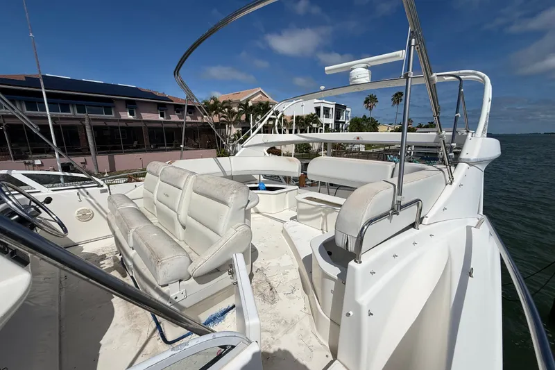 Slide: The Image of 2004 Silverton 43 Motor Yacht with spacious seating on deck, docked by waterfront homes. - 63