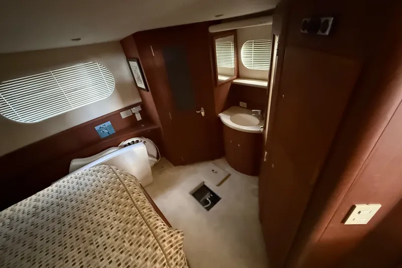 Slide: The Image of 2004 Silverton 43 Motor Yacht interior cabin with bed, window, and bathroom sink. - 141