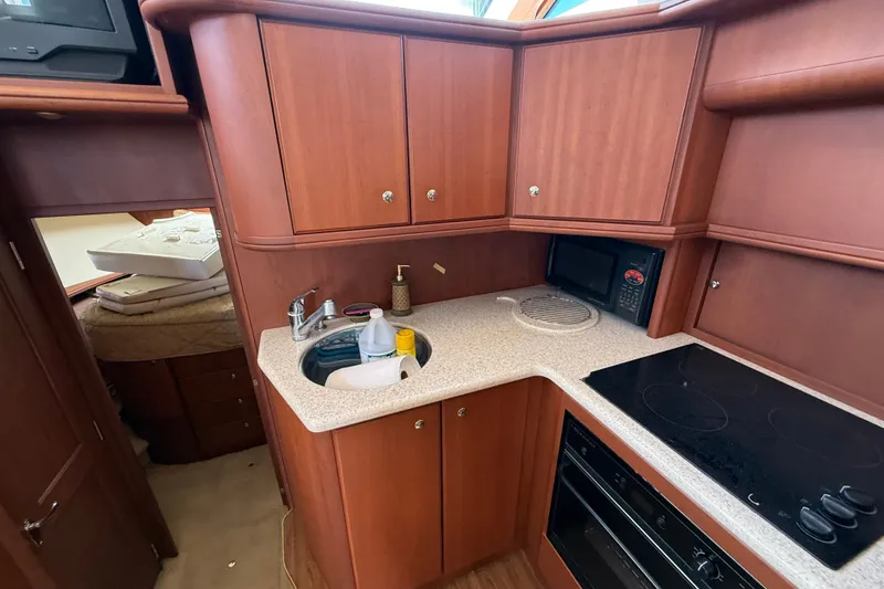 Slide: The Image of 2004 Silverton 43 Motor Yacht kitchen with wood cabinetry, sink, and appliances. - 104