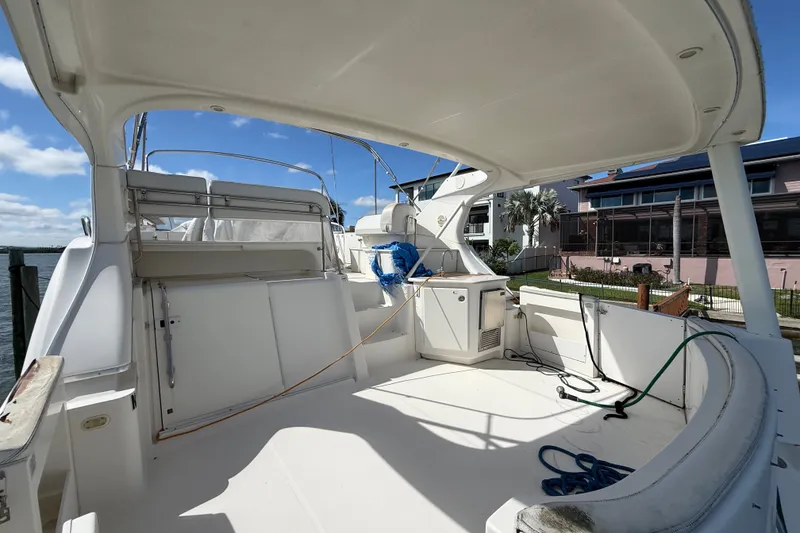 Slide: The Image of 2004 Silverton 43 Motor Yacht deck with seating and storage, docked by waterfront homes. - 8