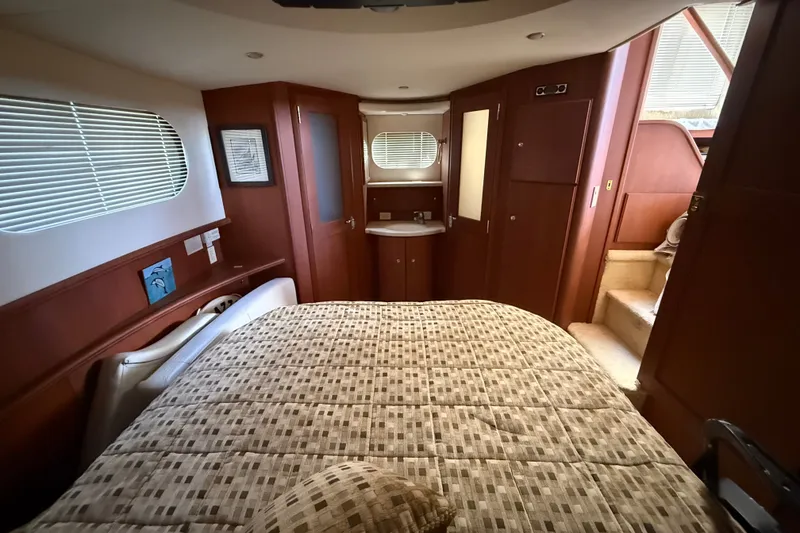 Slide: The Image of Luxurious cabin interior of 2004 Silverton 43 Motor Yacht with cozy bed and wooden accents. - 165