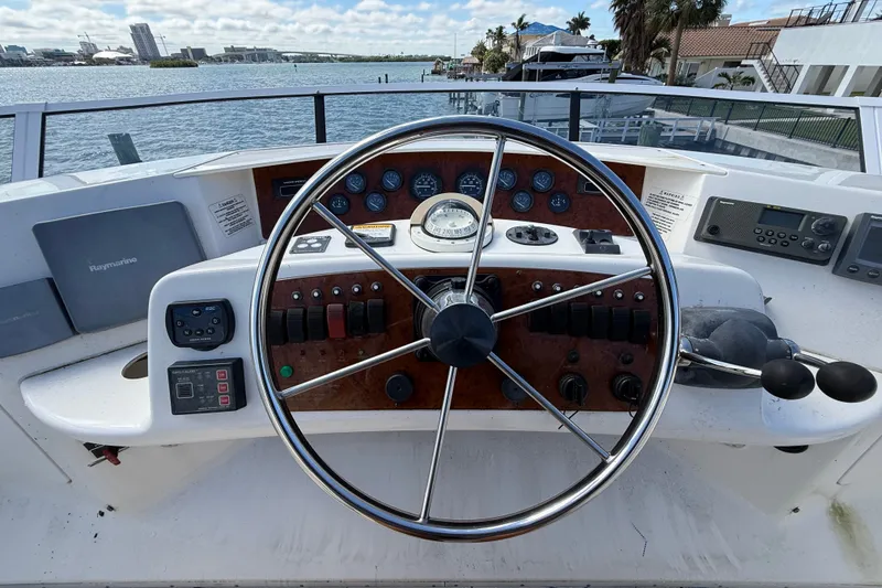 Slide: The Image of 2004 Silverton 43 Motor Yacht helm with steering wheel and control panel, overlooking waterfront. - 29