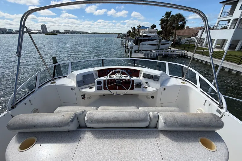 Slide: The Image of 2004 Silverton 43 Motor Yacht helm with waterfront view, featuring steering wheel and controls. - 26