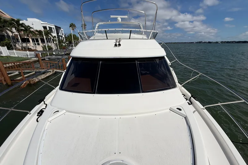 Slide: The Image of 2004 Silverton 43 Motor Yacht docked by waterfront homes under a blue sky. - 57